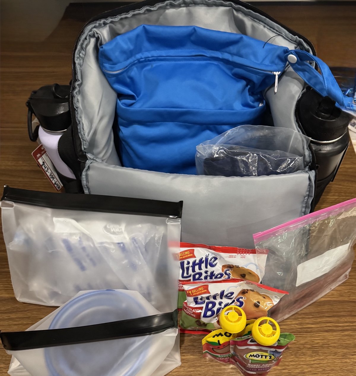 Our packed park bag with reusable snack pouches, muffin packs, applesauce pouches, and water bottles ready for a Disney park day