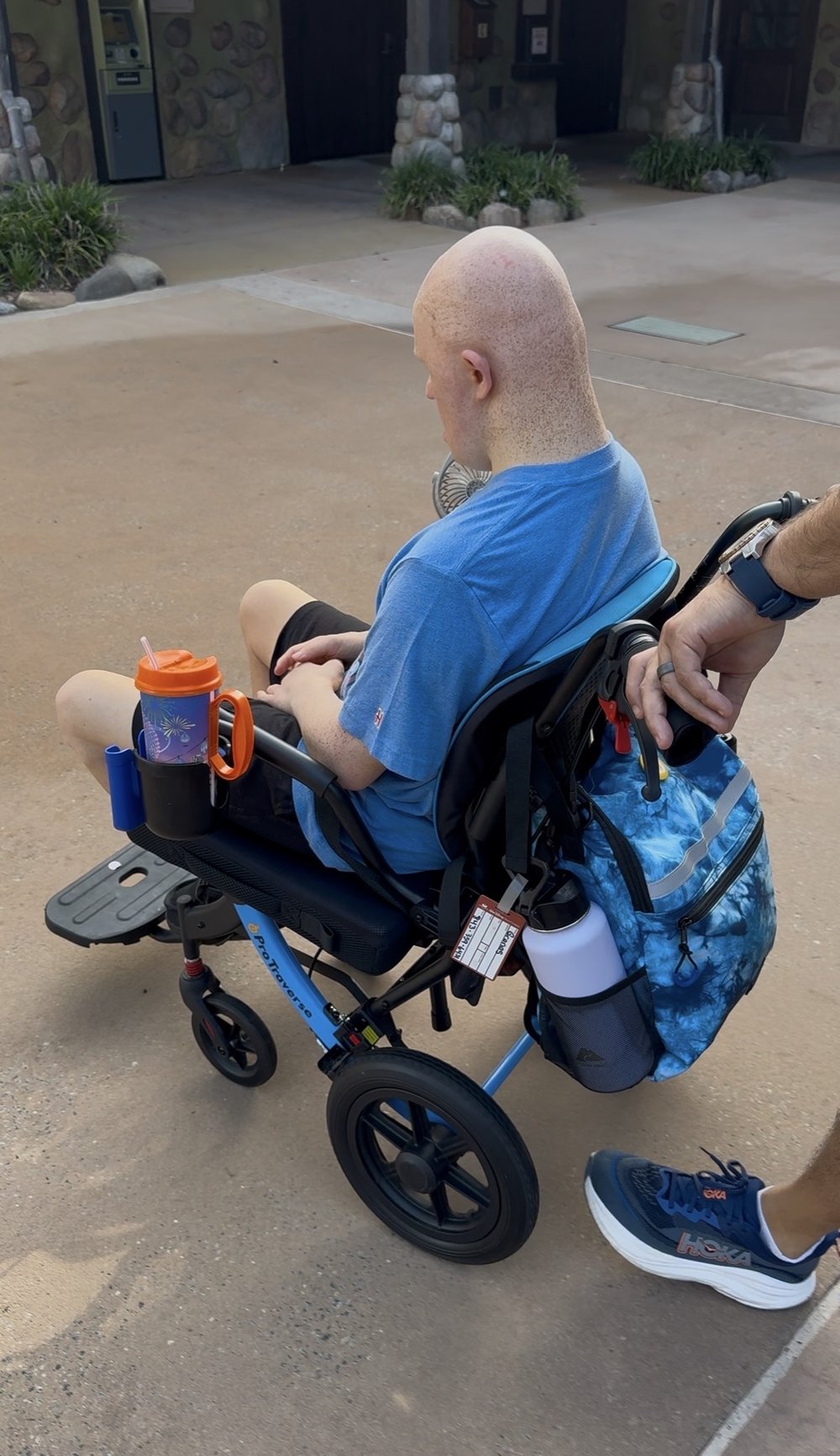 Our family's wheelchair fitted with a packed park bag, cup holders, and water bottle for a day at Disney