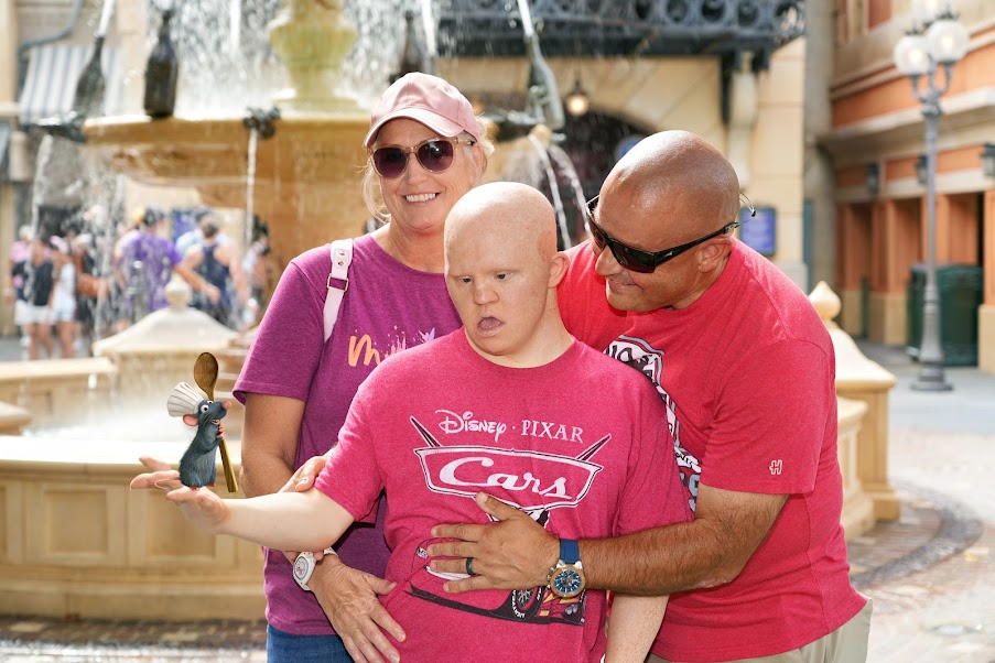 Sometimes the best PhotoPass pictures are the ones we never could have taken ourselves. Getting Seth to hold his hand out just right for this Remy Magic Shot was half the fun. 😂 Vanessa, Troy and Seth pose together near a fountain at EPCOT while Seth holds out his hand for a Disney PhotoPass Remy Magic Shot.